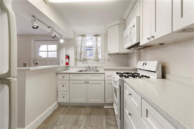 710 Burdette St, New Orleans, LA 70118 - kitchen featuring decorative backsplash, white cabinets, light wood-style flooring, white appliances, and a sink