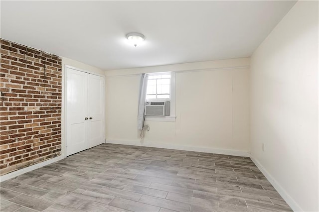710 Burdette St, New Orleans, LA 70118 - unfurnished room featuring cooling unit, baseboards, brick wall, and light wood finished floors