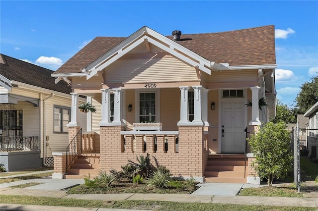 view of front of home featuring brick siding, a porch, and a shingled roof