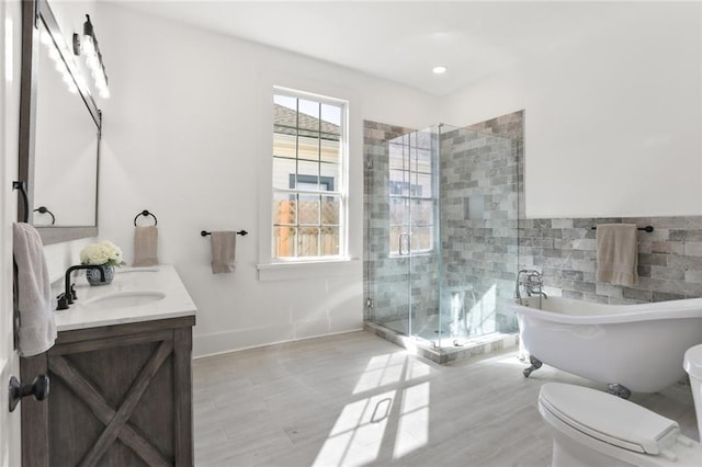 full bathroom with a soaking tub, vanity, toilet, wood finished floors, and a stall shower