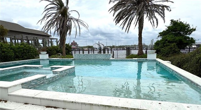 view of swimming pool with a pool with connected hot tub and fence