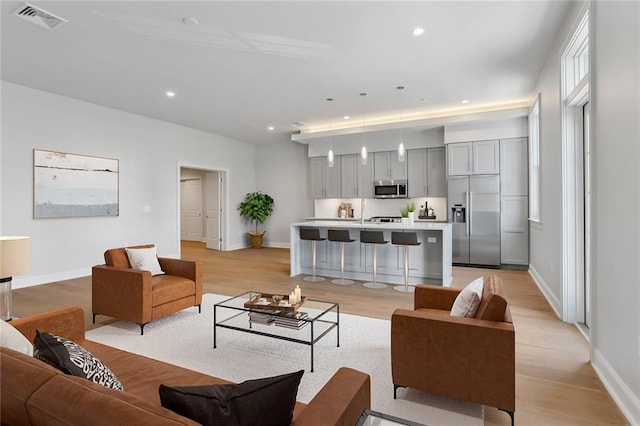 living area featuring recessed lighting, baseboards, visible vents, and light wood-type flooring