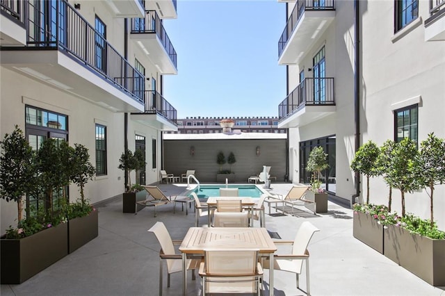 view of patio / terrace featuring a balcony and an outdoor pool