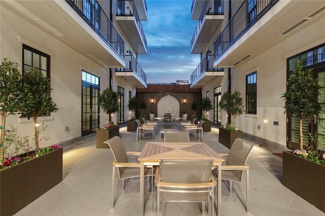 patio terrace at dusk featuring outdoor dining area and a balcony
