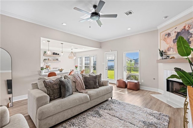 313 Oak Point Dr, La Place, LA 70068 - living room featuring light wood-style floors, crown molding, a tile fireplace, baseboards, and ceiling fan
