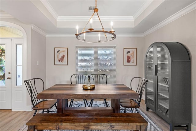 313 Oak Point Dr, La Place, LA 70068 - dining room with a tray ceiling, light wood-style flooring, a chandelier, crown molding, and arched walkways