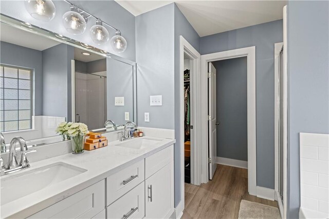 313 Oak Point Dr, La Place, LA 70068 - full bathroom featuring a shower stall, wood finished floors, double vanity, and a spacious closet
