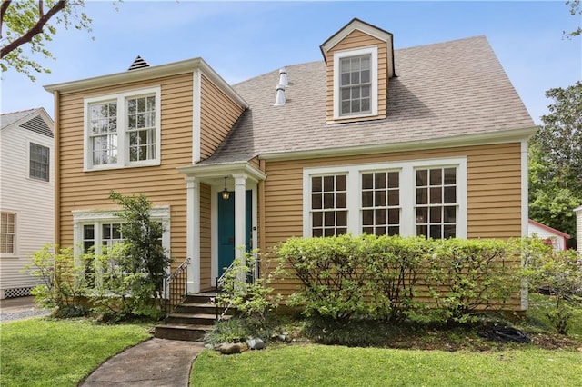 view of front of property featuring a shingled roof and a front yard