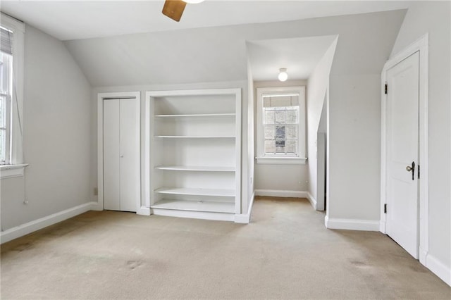 unfurnished bedroom with vaulted ceiling, carpet flooring, baseboards, and multiple windows