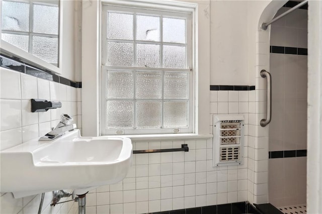 bathroom with a shower stall and tile walls