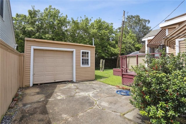 exterior space with an outdoor structure, aphalt driveway, a wooden deck, and a detached garage