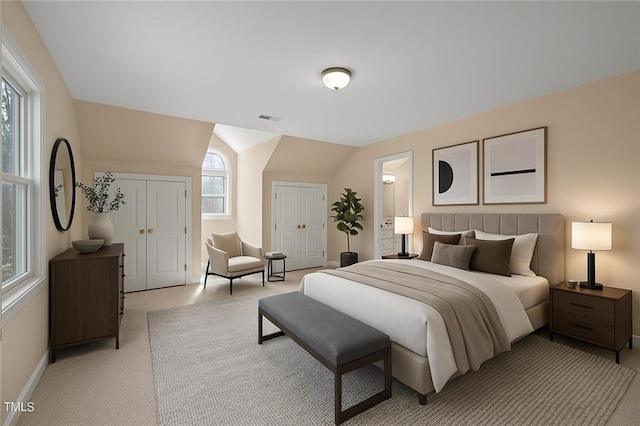 bedroom with vaulted ceiling, visible vents, light carpet, ensuite bath, and baseboards