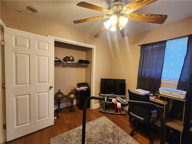 office space featuring a ceiling fan, baseboards, and wood finished floors