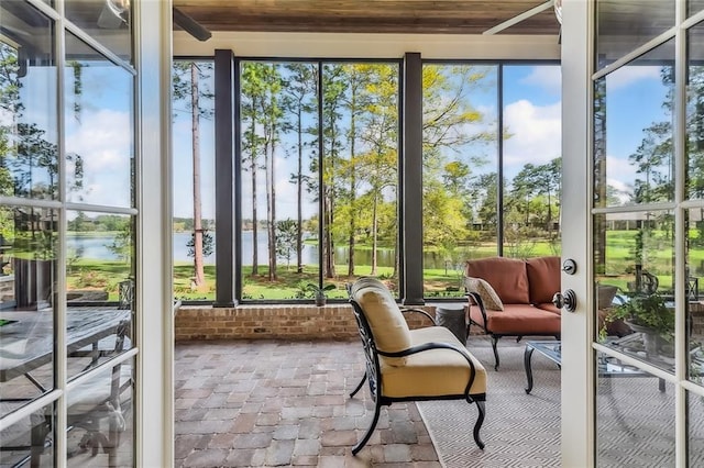 sunroom / solarium with a water view and brick floor