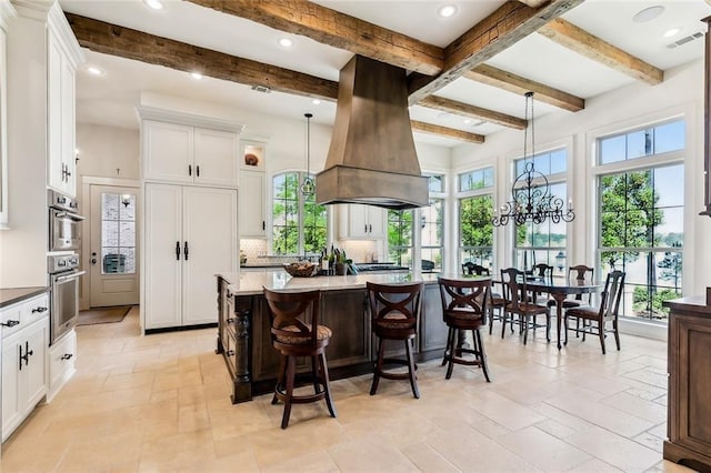 kitchen featuring island range hood, tasteful backsplash, visible vents, and white cabinetry