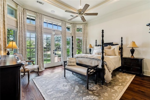 bedroom featuring access to exterior, dark wood-style floors, visible vents, and a tray ceiling