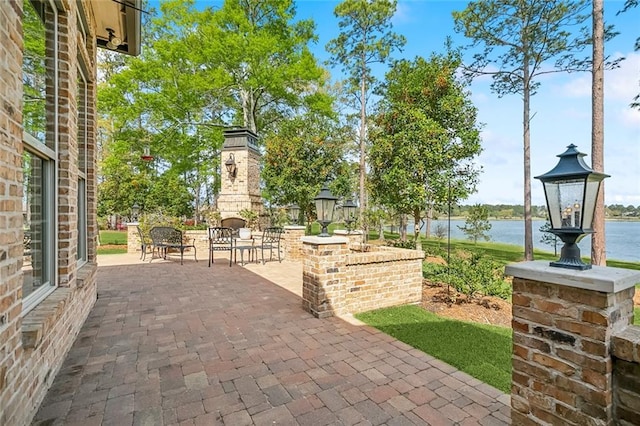view of patio / terrace with an outdoor brick fireplace and a water view