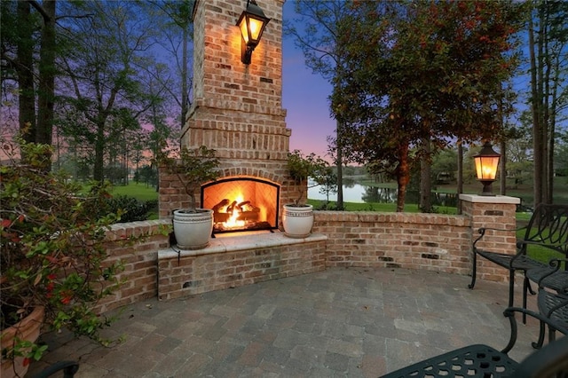 view of patio with an outdoor brick fireplace and a water view