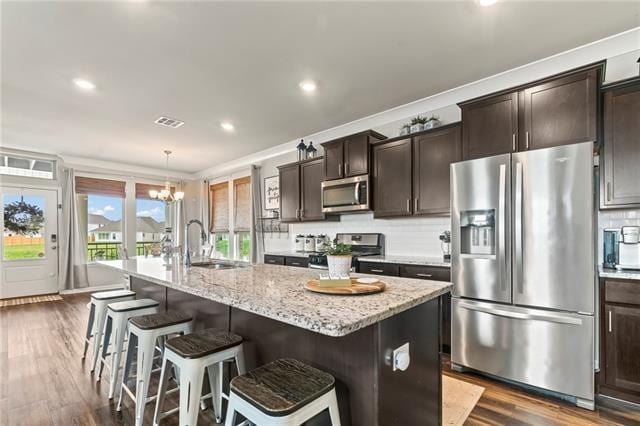405 Short Bough Ln, Slidell, LA 70461 - kitchen with stainless steel appliances, dark wood-type flooring, tasteful backsplash, a kitchen bar, and dark brown cabinetry