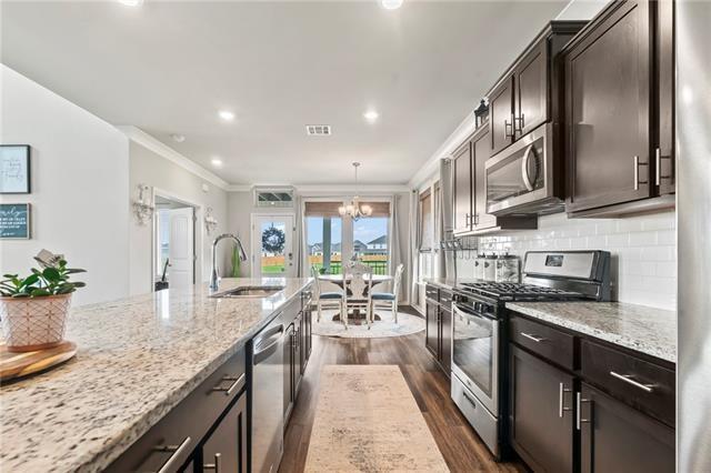 405 Short Bough Ln, Slidell, LA 70461 - kitchen featuring stainless steel appliances, a chandelier, crown molding, dark wood-type flooring, and light stone counters