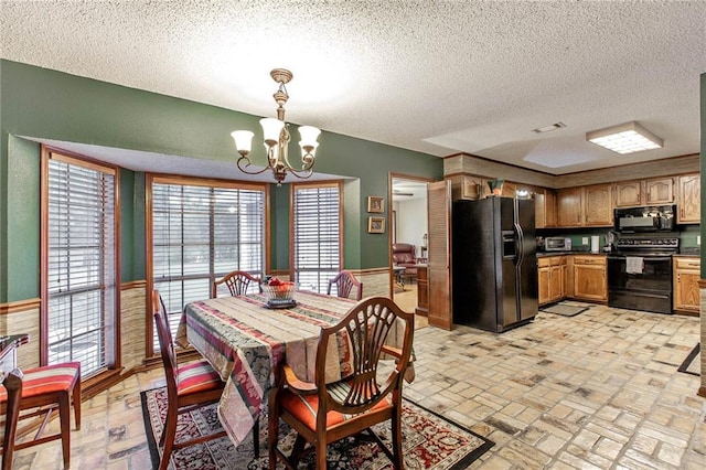 706 Natalie Dr, Houma, LA 70364 - dining space with a chandelier, a textured ceiling, a wainscoted wall, brick floor, and visible vents