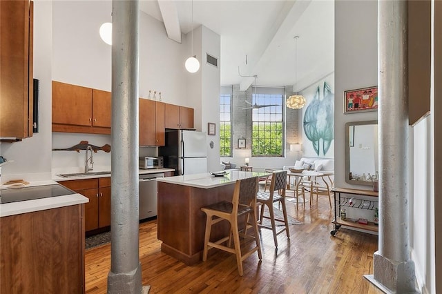 kitchen featuring visible vents, freestanding refrigerator, wood finished floors, a sink, and dishwasher