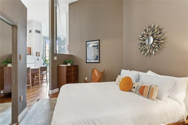 bedroom featuring baseboards, wood finished floors, and visible vents