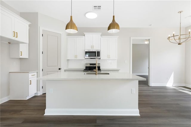 35378 Liberty Dr, Slidell, LA 70460 - kitchen featuring stainless steel appliances, a sink, dark wood finished floors, white cabinets, and a center island with sink