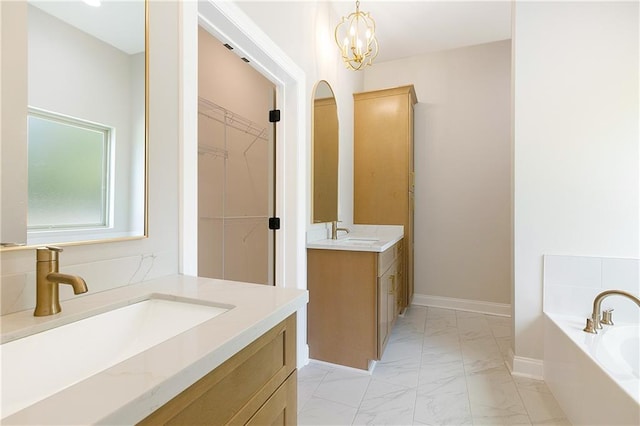 35378 Liberty Dr, Slidell, LA 70460 - full bathroom with marble finish flooring, two vanities, a garden tub, baseboards, and a walk in closet