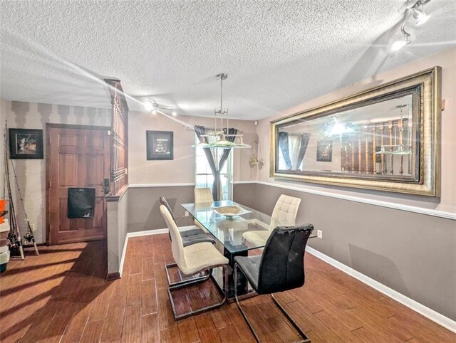 632 Fairlawn Dr, Terrytown, LA 70056 - dining room featuring baseboards, a textured ceiling, rail lighting, and wood finished floors
