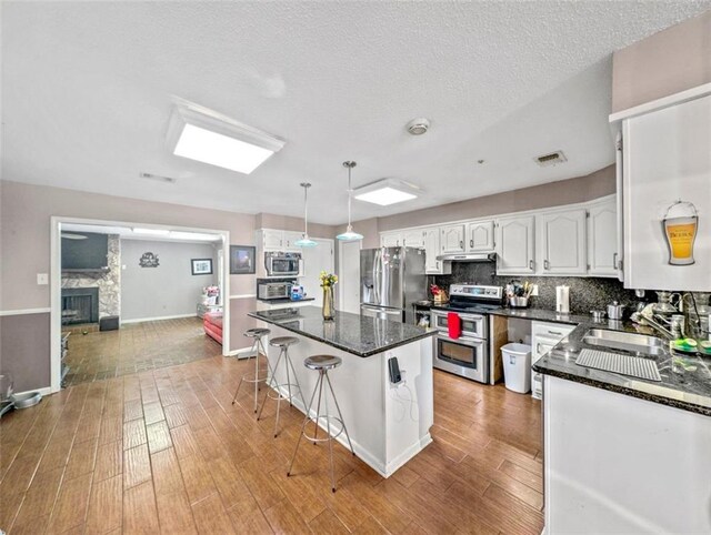 632 Fairlawn Dr, Terrytown, LA 70056 - kitchen featuring decorative backsplash, white cabinets, visible vents, light wood finished floors, and stainless steel appliances