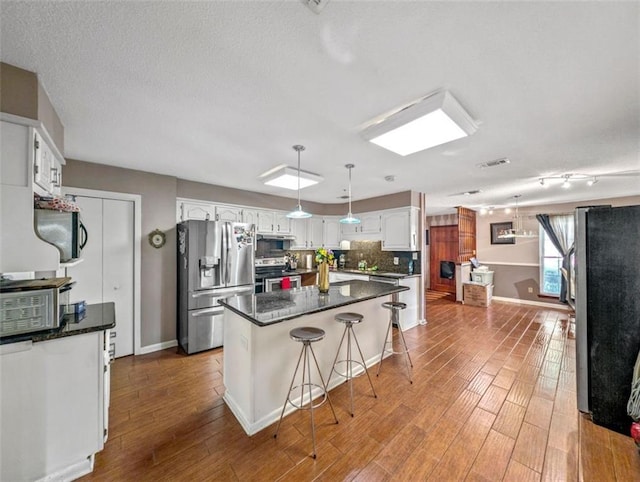 632 Fairlawn Dr, Terrytown, LA 70056 - kitchen with backsplash, white cabinets, appliances with stainless steel finishes, and wood finished floors