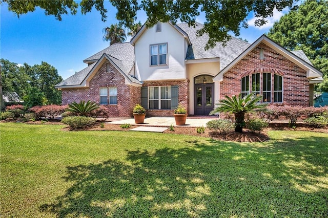 view of front of home with a front lawn, a shingled roof, and brick siding