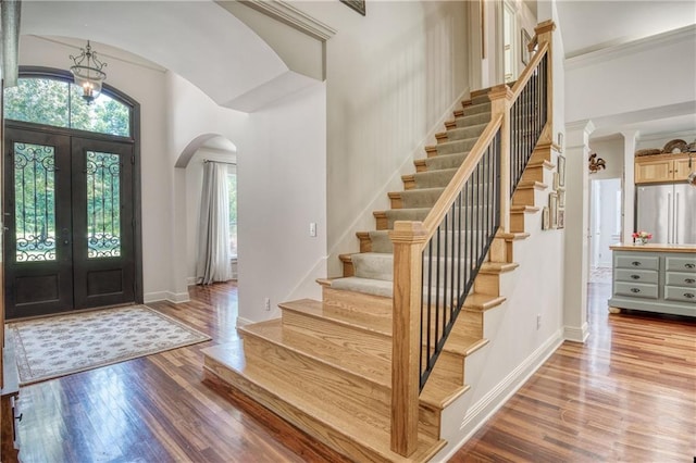 entrance foyer featuring stairs, light wood-type flooring, arched walkways, and a healthy amount of sunlight
