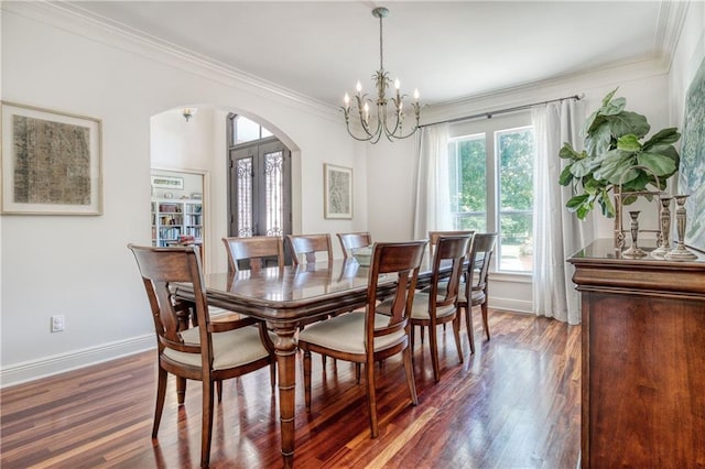 dining area featuring crown molding, a chandelier, wood finished floors, baseboards, and arched walkways