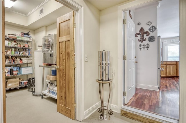 hall featuring crown molding, wood finished floors, washer / dryer, baseboards, and visible vents