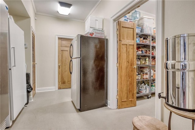 interior space with freestanding refrigerator, crown molding, and baseboards