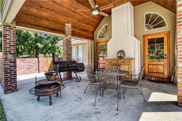 view of patio / terrace with a fire pit, outdoor dining area, fence, and ceiling fan