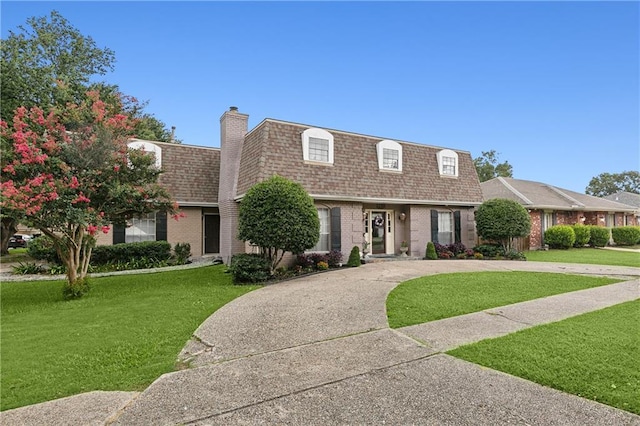 1100 Vintage Dr, Kenner, LA 70065 - view of front of home with brick siding, mansard roof, a front lawn, roof with shingles, and curved driveway