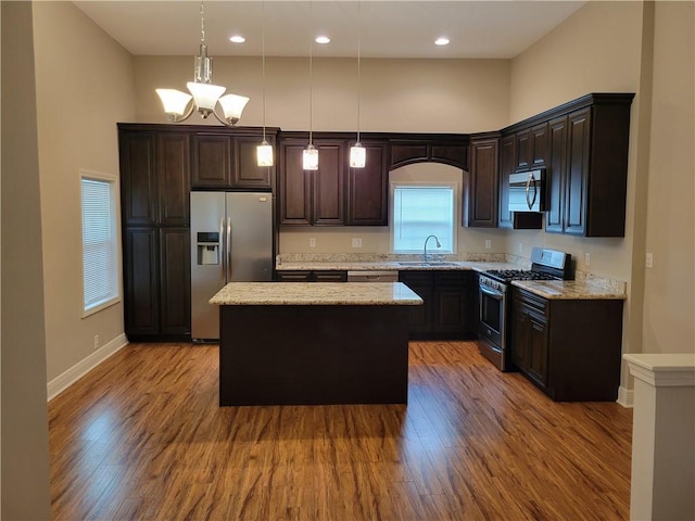 kitchen with a kitchen island, a sink, stainless steel appliances, and wood finished floors