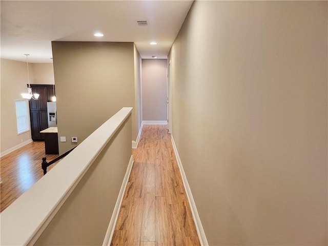 305 Amapola Cir, Terrytown, LA 70056 - hallway with light wood finished floors, a chandelier, recessed lighting, an upstairs landing, and baseboards
