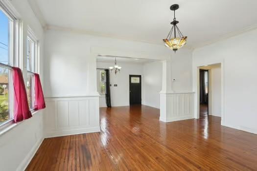 4674 Venus St, New Orleans, LA 70122 - empty room with a chandelier, wood finished floors, a wainscoted wall, and a decorative wall