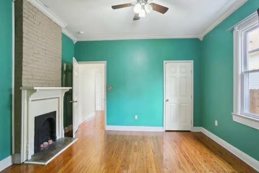 4674 Venus St, New Orleans, LA 70122 - unfurnished living room featuring ceiling fan, crown molding, wood finished floors, and a fireplace with raised hearth
