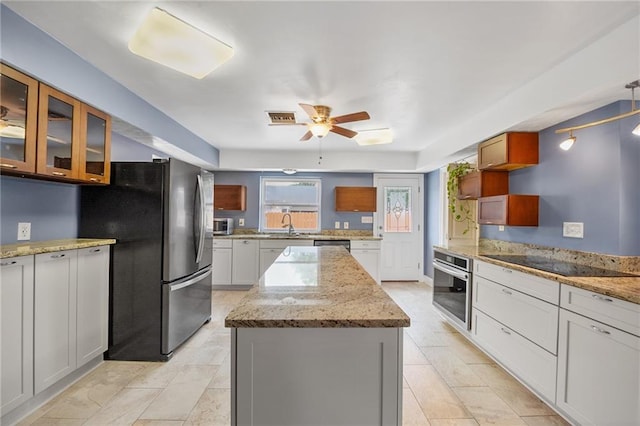 212 Somerset St, La Place, LA 70068 - kitchen with stainless steel appliances, ceiling fan, a kitchen island, glass insert cabinets, and light stone counters