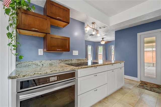 kitchen featuring white cabinets, oven, a peninsula, black electric stovetop, and light stone countertops