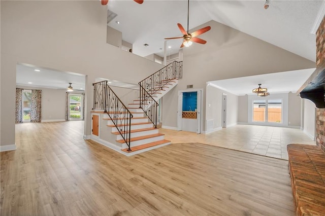 212 Somerset St, La Place, LA 70068 - unfurnished living room featuring ceiling fan, high vaulted ceiling, stairs, light wood-style floors, and baseboards