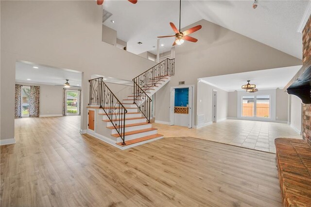 212 Somerset St, La Place, LA 70068 - unfurnished living room featuring a ceiling fan, high vaulted ceiling, stairway, plenty of natural light, and light wood-style flooring