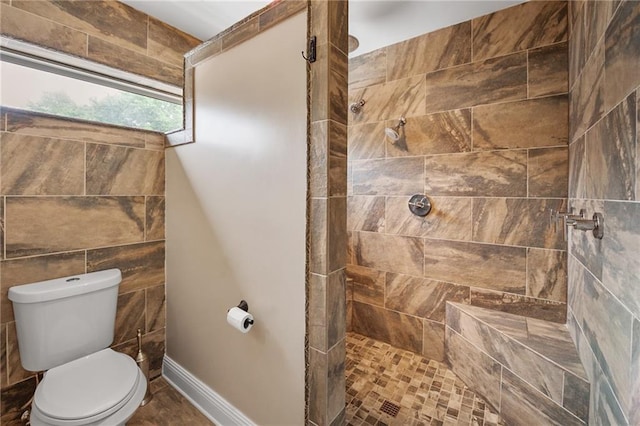 full bathroom featuring tiled shower, baseboards, and toilet