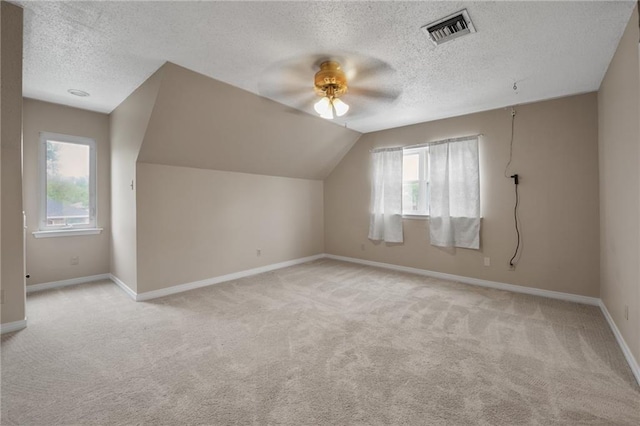 bonus room with ceiling fan, a textured ceiling, visible vents, light carpet, and baseboards