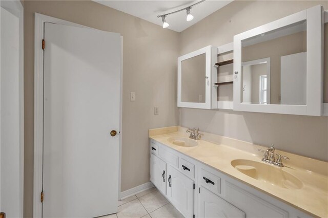 bathroom featuring tile patterned floors, double vanity, baseboards, and a sink